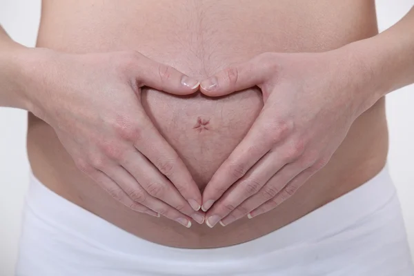 妊娠中の女性が彼女の胃に心臓の形を作る — ストック写真