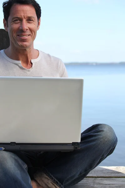 Άνθρωπος χρησιμοποιώντας ένα φορητό υπολογιστή στην προκυμαία — Φωτογραφία Αρχείου