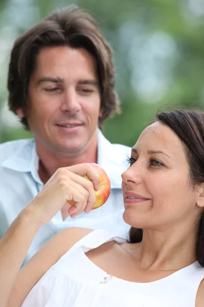 Пара отдыха в парке и есть яблоко — стоковое фото