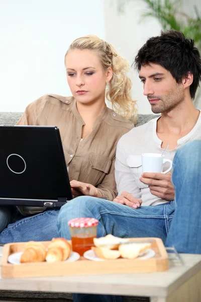 Casal com laptop tomando café da manhã — Fotografia de Stock