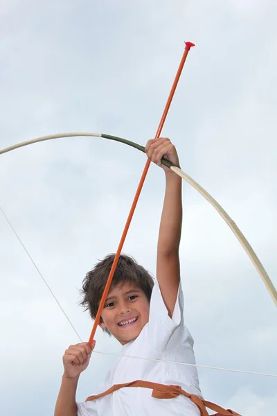 Счастливый маленький мальчик играет со стрелами и луком — стоковое фото