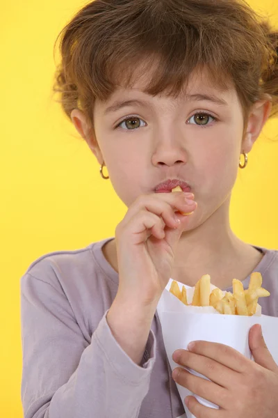 Το κοριτσάκι τρώει τηγανιτές πατάτες. — Φωτογραφία Αρχείου
