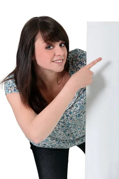Adolescente menina apontando para um sinal branco — Fotografia de Stock