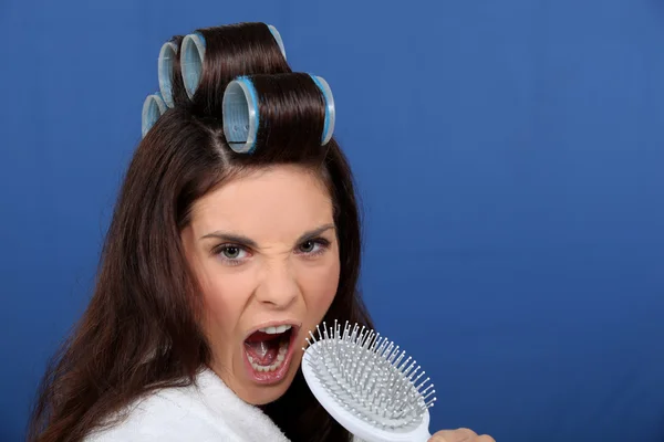 Žena s natáčky v její vlasy zpěv — Stock fotografie