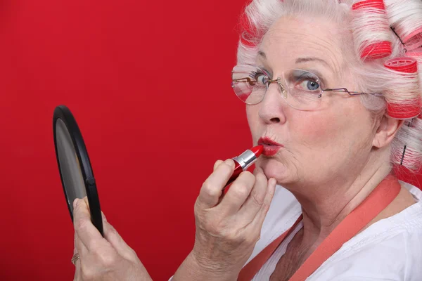 老婦人は口紅を適用します。 — ストック写真