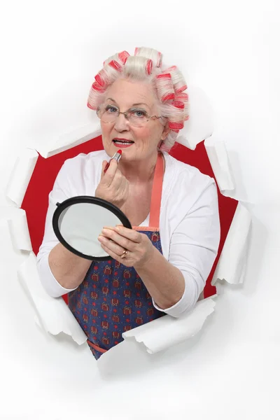 Old woman in rollers putting on lipstick — Stock Photo, Image