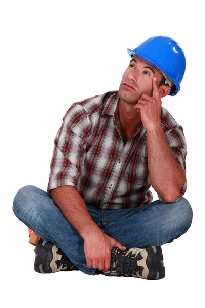 Pensive laborer sitting on white background — Stock Photo, Image