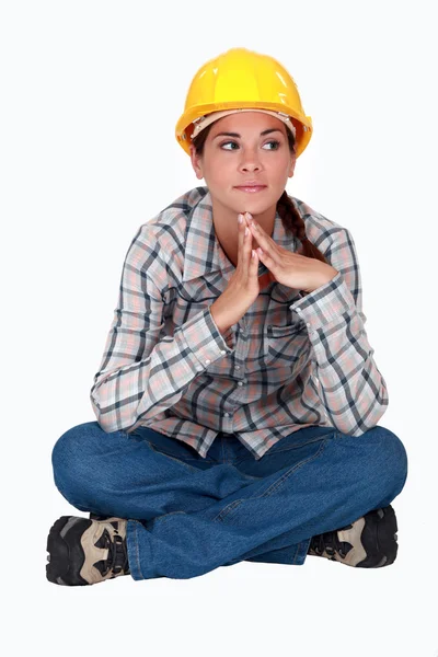 Pensivo mulher construtor sentou-se de pernas cruzadas — Fotografia de Stock