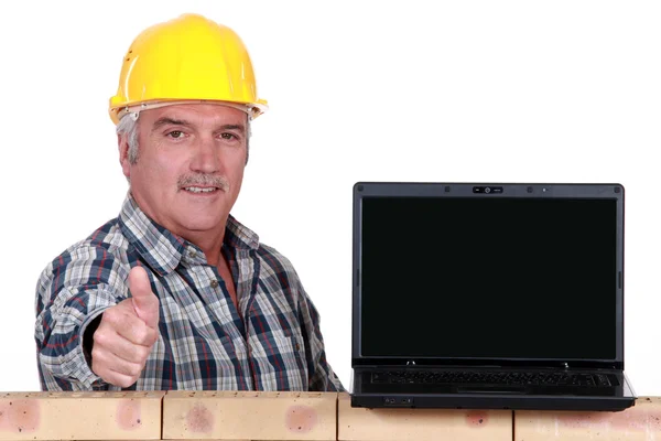 Builder ger tummen upp till en bärbar dator med en tom skärm — Stockfoto