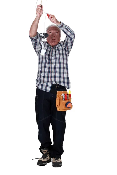 Homem eletrocutado fixando um dispositivo elétrico de luz — Fotografia de Stock