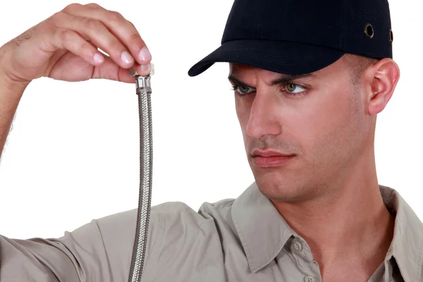 Klempner schaut auf ein flexibles Rohr — Stockfoto