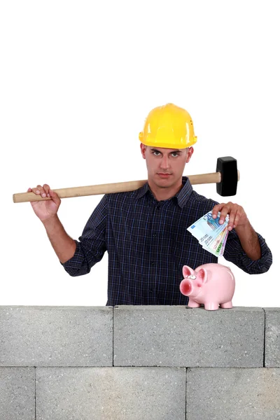 Trabalhador da construção colocando dinheiro em um banco porquinho — Fotografia de Stock