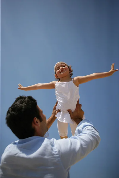 Hombre levantando a su hija en el aire — Foto de Stock