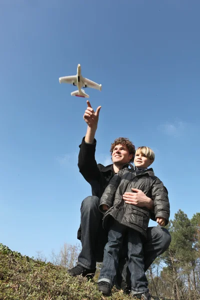 Молодые отец и сын играют в игрушечный самолет на открытом воздухе — стоковое фото