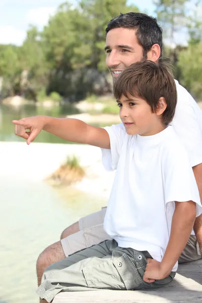 Baba ve oğul bir göl kenarında oturan — Stok fotoğraf