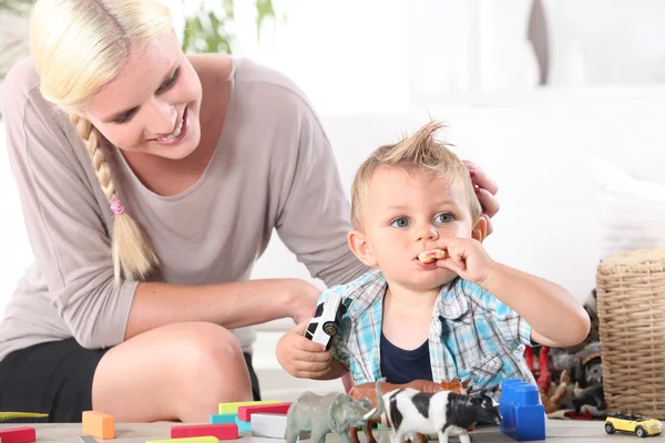 Mother watching son playing with toys — Stock Photo, Image