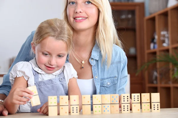 En mor och dotter leker med dominos. — Stockfoto
