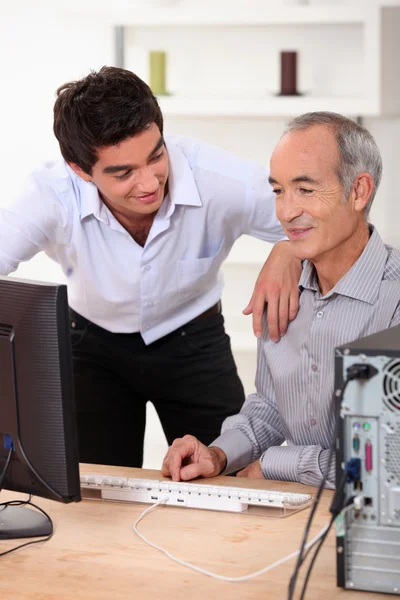 Сын помогает отцу с компьютером — стоковое фото