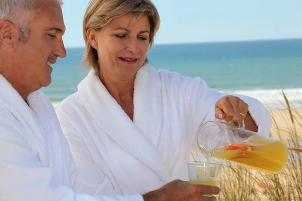 Зрелая пара, пьющая на пляже — стоковое фото