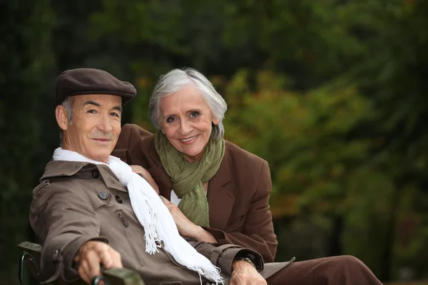Elegantní starší pár sedící na lavičce v parku — Stock fotografie