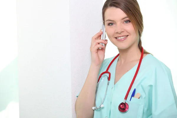 Sjuksköterska leende på telefon — Stockfoto
