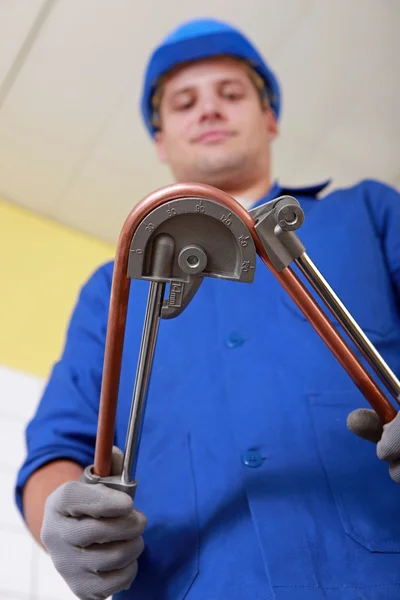 Tradesman using a tool to bend a copper tool — Stock Photo, Image
