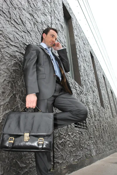 Uomo d'affari per strada con una valigetta e un cellulare — Foto Stock