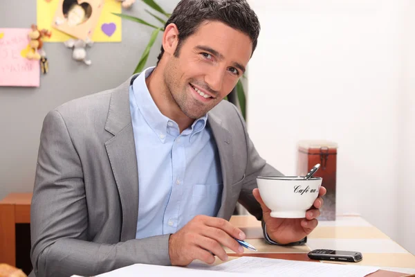 Empresário trabalhando em sua cozinha com uma xícara de café — Fotografia de Stock