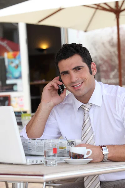Businessman drinking an expresso in a cafe while talking on a cellphone — Stock Photo, Image