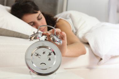 Woman turning off alarm clock clipart