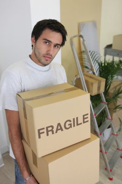 Young man carrying cardboard boxes on moving day clipart