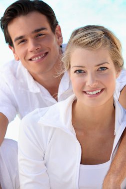 Smiling young couple dressed in white on a summer's day clipart