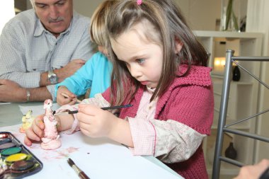 Little girl painting a figurine clipart