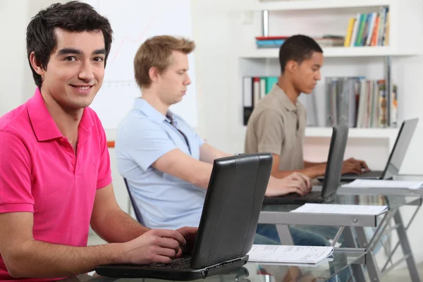Unga män som arbetar på deras uppdrag i en datorsal — Stockfoto
