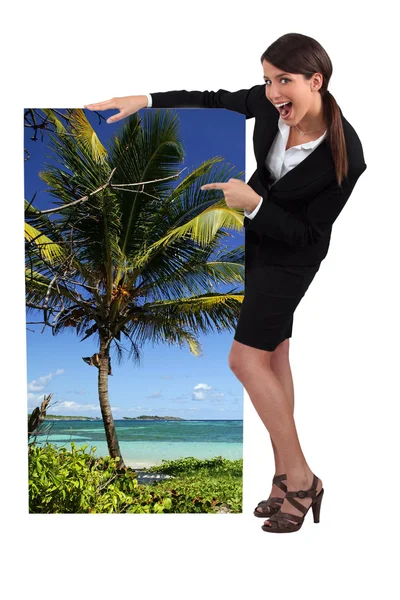 Mujer agente de viajes mostrando póster de playa tropical —  Fotos de Stock