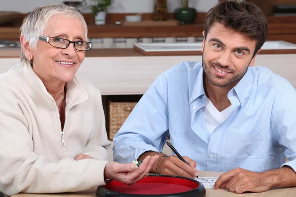 Jonge man spelen dobbelstenen met oudere vrouw — Stockfoto