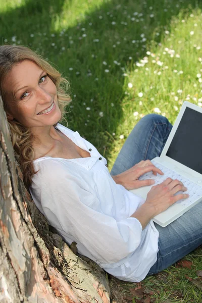 Gyönyörű szőke támaszkodva fa dolgozik laptop portréja — Stock Fotó