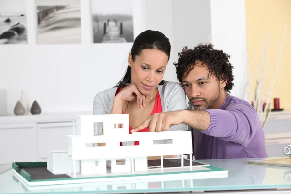 Casal olhando para um modelo de arquiteto de um novo desenvolvimento — Fotografia de Stock