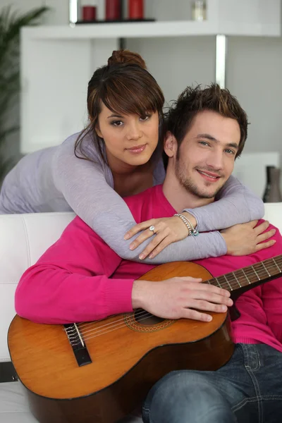 Młoda para w pomieszczeniu z gitarą — Zdjęcie stockowe