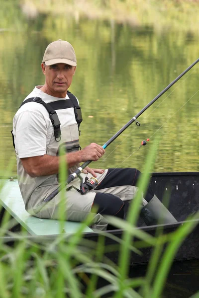 Hombre pescando en un barco en un río — Foto de Stock