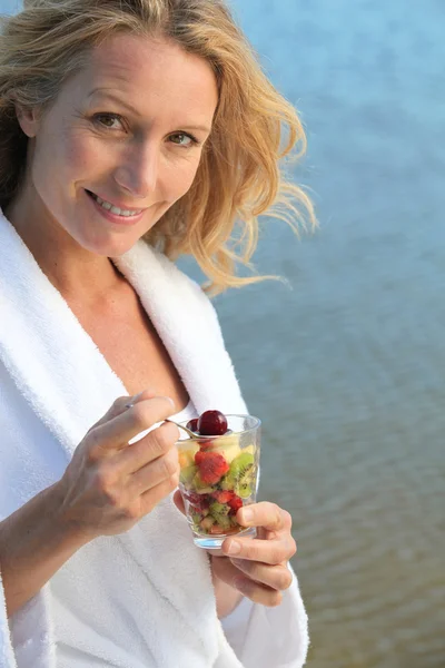 Femme mangeant de la salade de fruits sur la plage — Photo