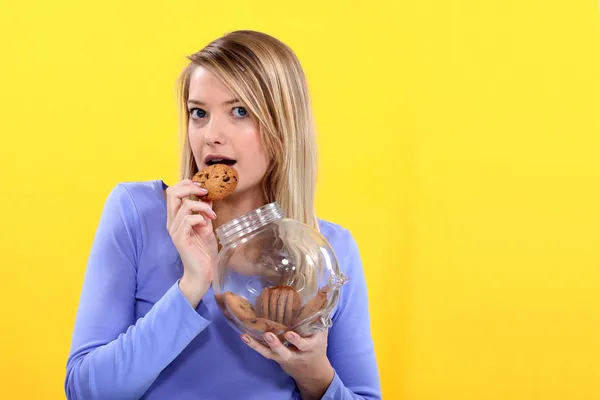 Donna che mangia biscotti dal barattolo — Foto Stock