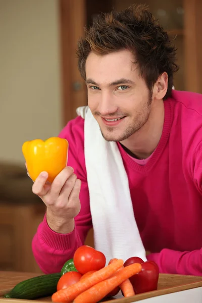 Junger Mann mit gelbem Paprika und anderem Gemüse — Stockfoto