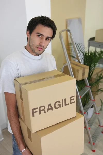 Taşınma günü üzerine karton kutu taşıyan genç adam — Stok fotoğraf