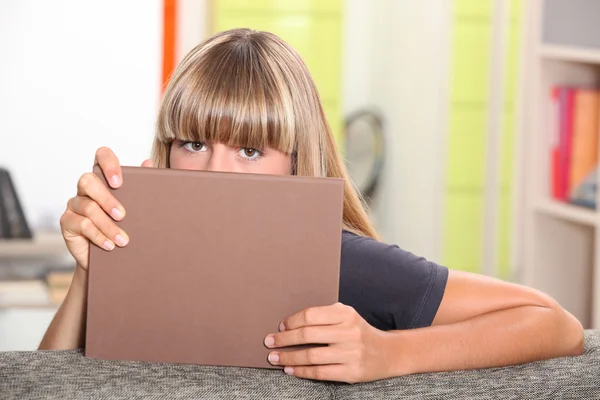 Adolescente se escondendo atrás de um livro . — Fotografia de Stock