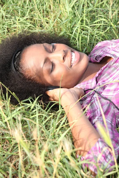 Genç kadın çimlerin üzerinde yatıyor. — Stok fotoğraf