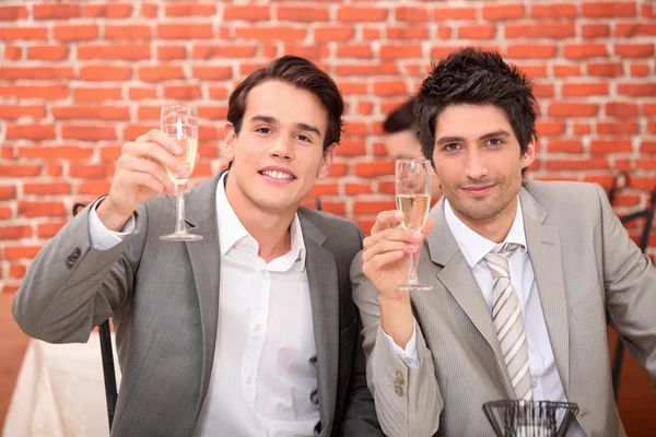Unga män i kostymer dricka champagne — Stockfoto