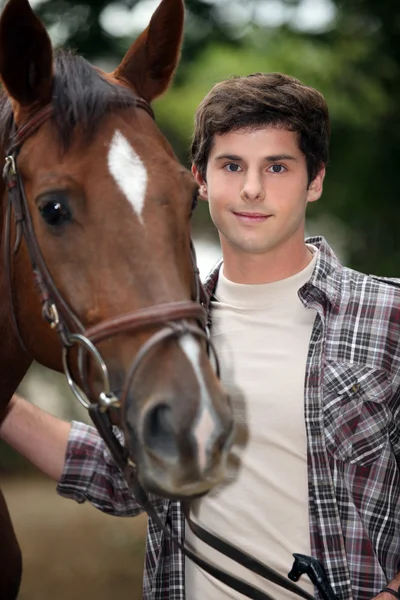 Junger Mann kümmert sich um sein Pferd — Stockfoto