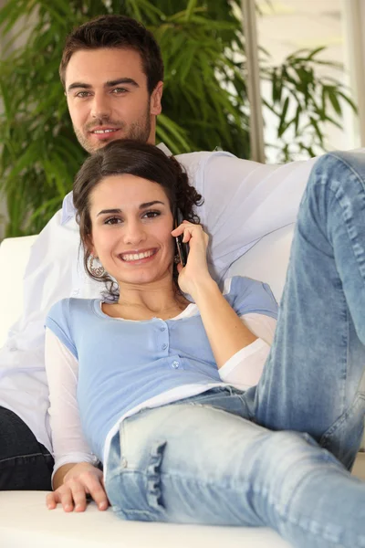 Casal fazendo chamada telefônica no sofá — Fotografia de Stock