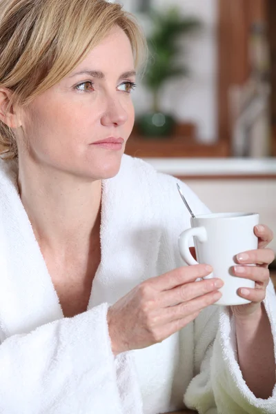 物思いにふける女性彼女のバスローブでコーヒーの朝のカップを持っています。 — ストック写真